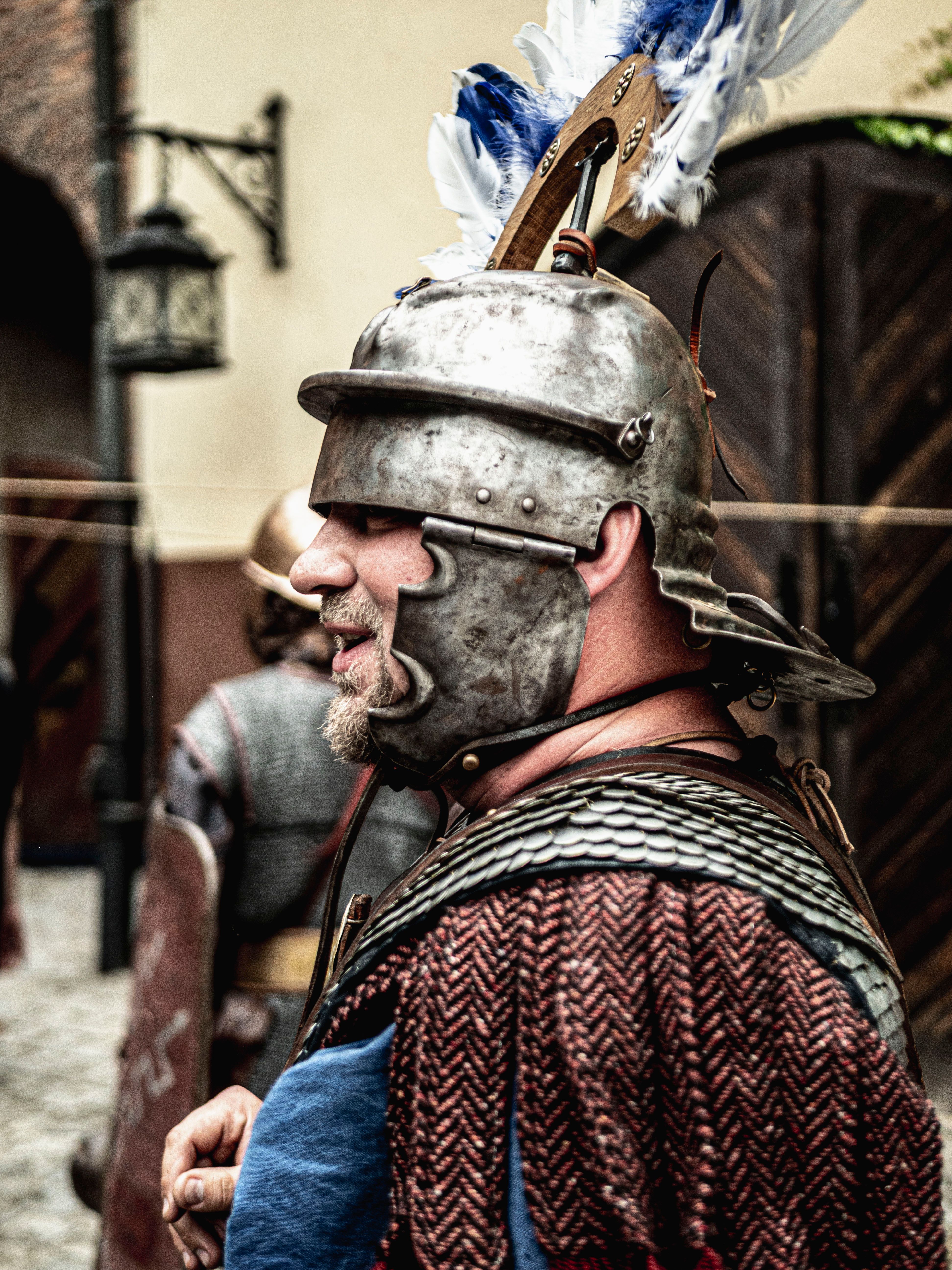 Adult male wearing medieval armor participates in a historical reenactment event.