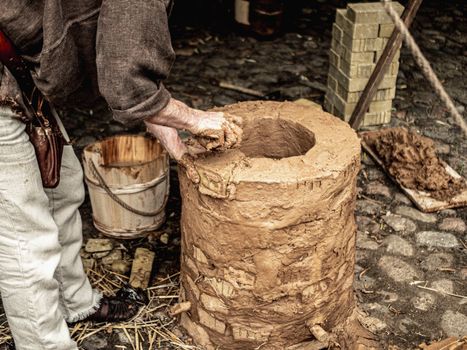 An artisan builds a clay oven using traditional techniques and natural materials.