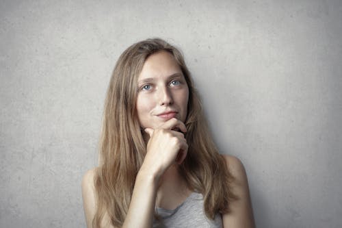 Free Woman in Gray Tank Top While Holding Her Chin Stock Photo