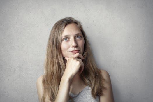 一位女人在灰色背景的简单肖像中，深思熟虑地思考着生活