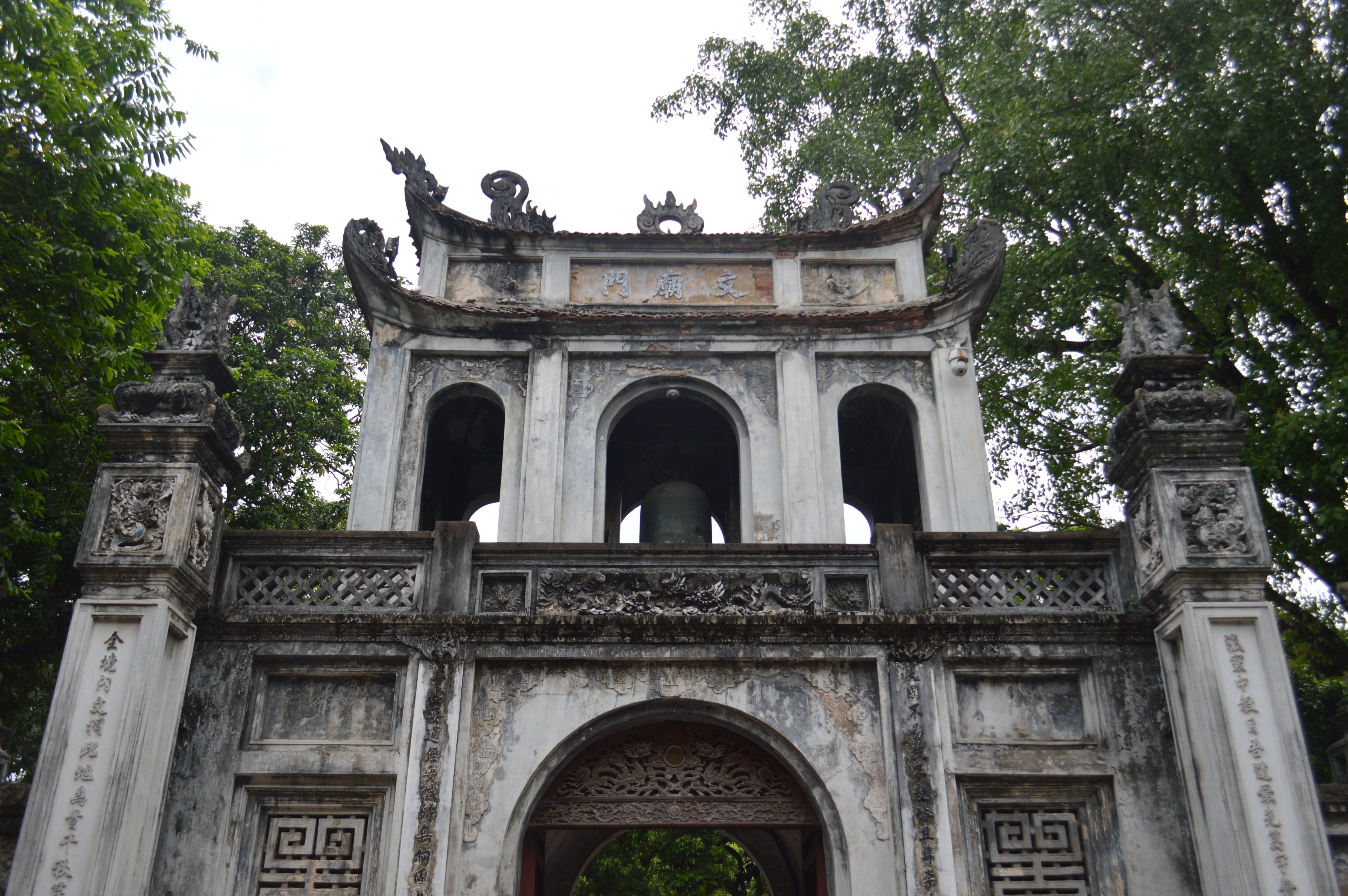 A historic stone gate at the Temple of Literature in Hanoi, Vietnam, featuring intricate carvings.