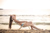 夏天，一名女子穿着比基尼在沙滩椅上晒日光浴