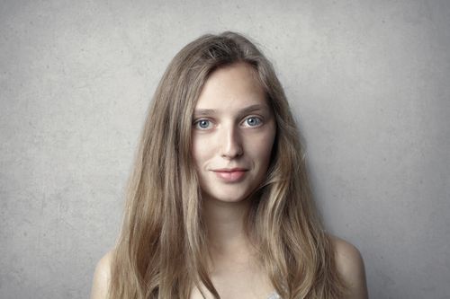 Free Close-up portrait of a smiling woman with long blonde hair against a gray background. Stock Photo