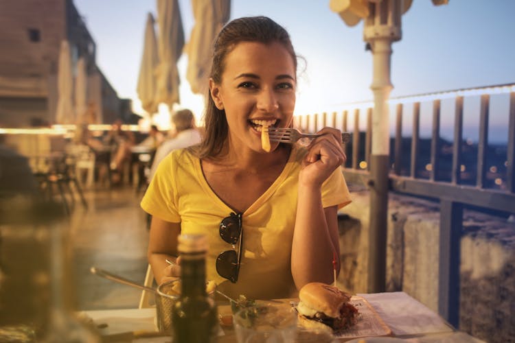 Woman In Yellow Crew Neck T-shirt Eating Burger