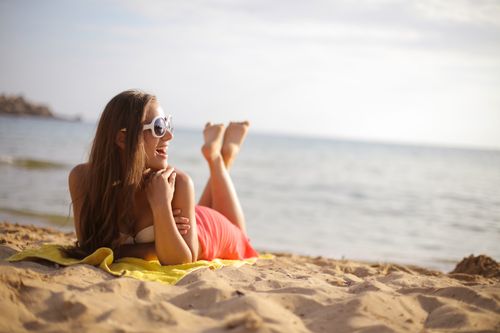 Free Enjoy carefree summer vibes with a young woman sunbathing on a sandy beach. Stock Photo