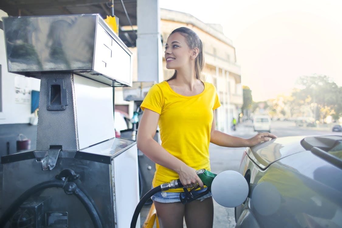 Free Woman in Yellow Shirt While Filling Up Her Car With Gasoline Stock Photo