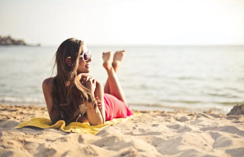 бесплатная Женщина улыбается, лежа на песке пляжа Стоковое фото