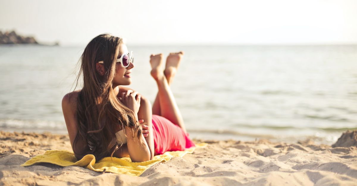 Mulher Sorrindo Enquanto Estava Deitada Na Areia Da Praia · Foto ...