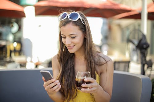 Wanita Memegang Ponsel Cerdas Dan Gelas Minum