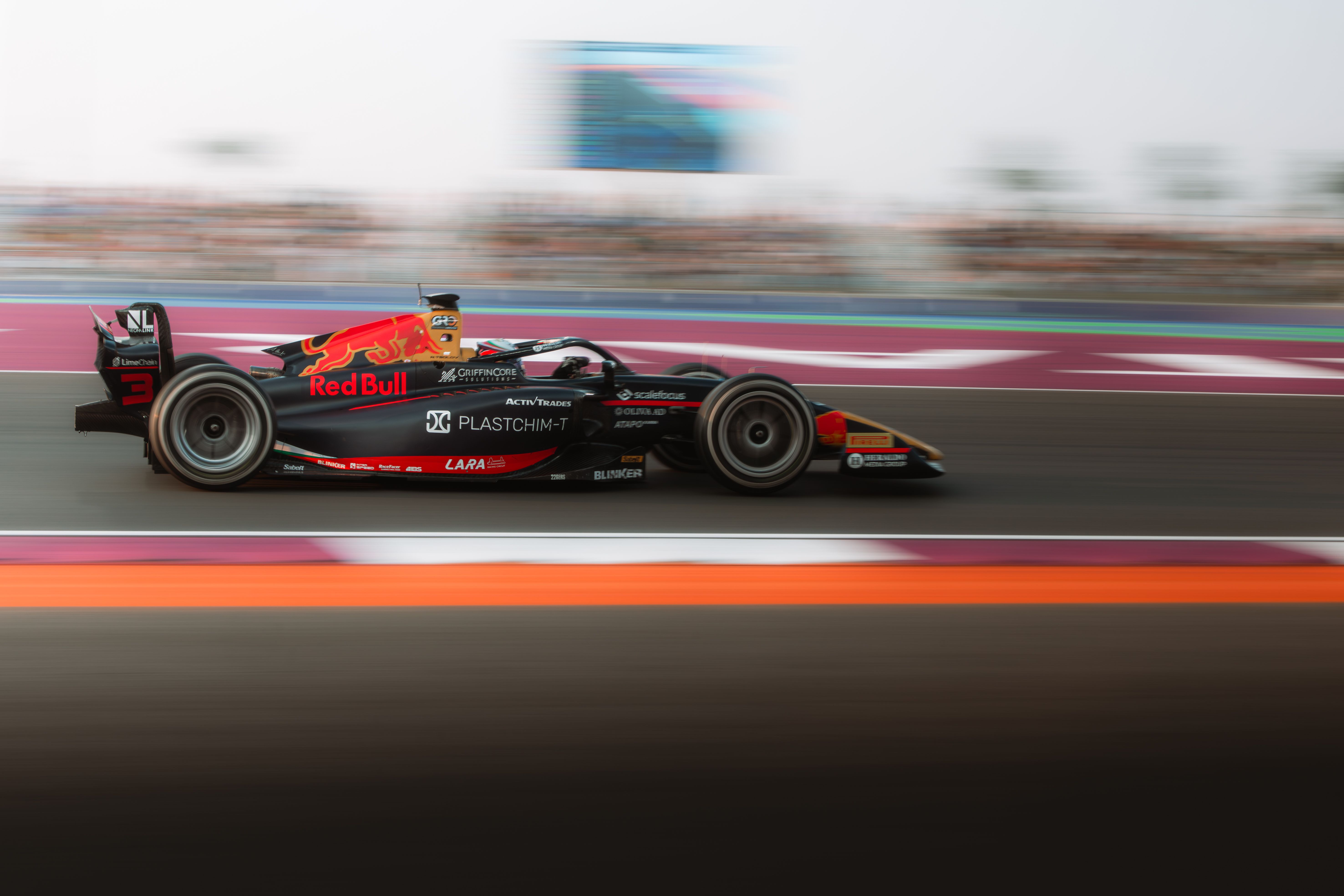 A high-speed racing car zooming down the track in Qatar, showcasing dynamic motion and excitement.