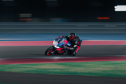 Free Dynamic action shot of a motorcycle racer speeding around the track at night. Stock Photo