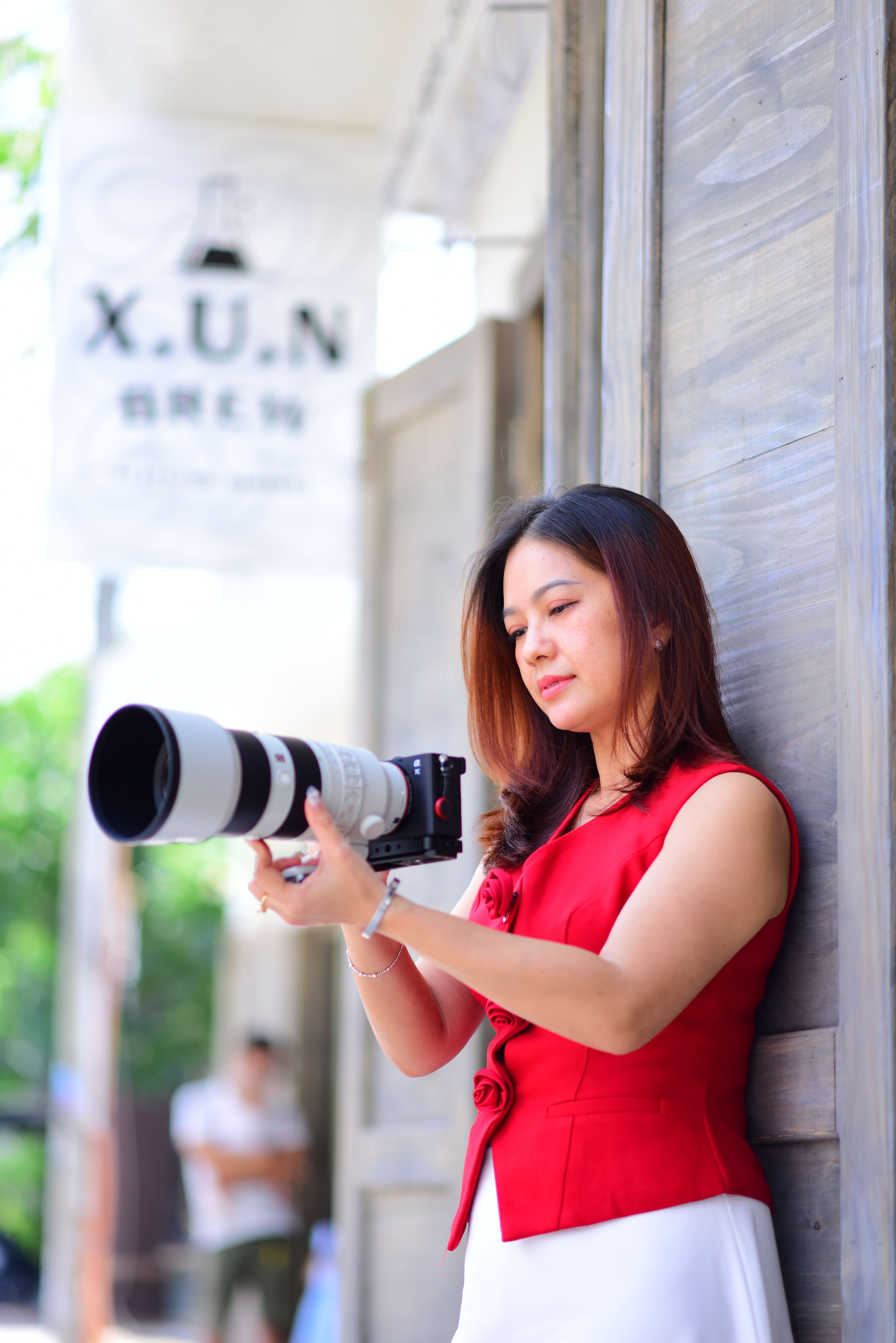 Portrait of a woman with camera in a vibrant city street setting.