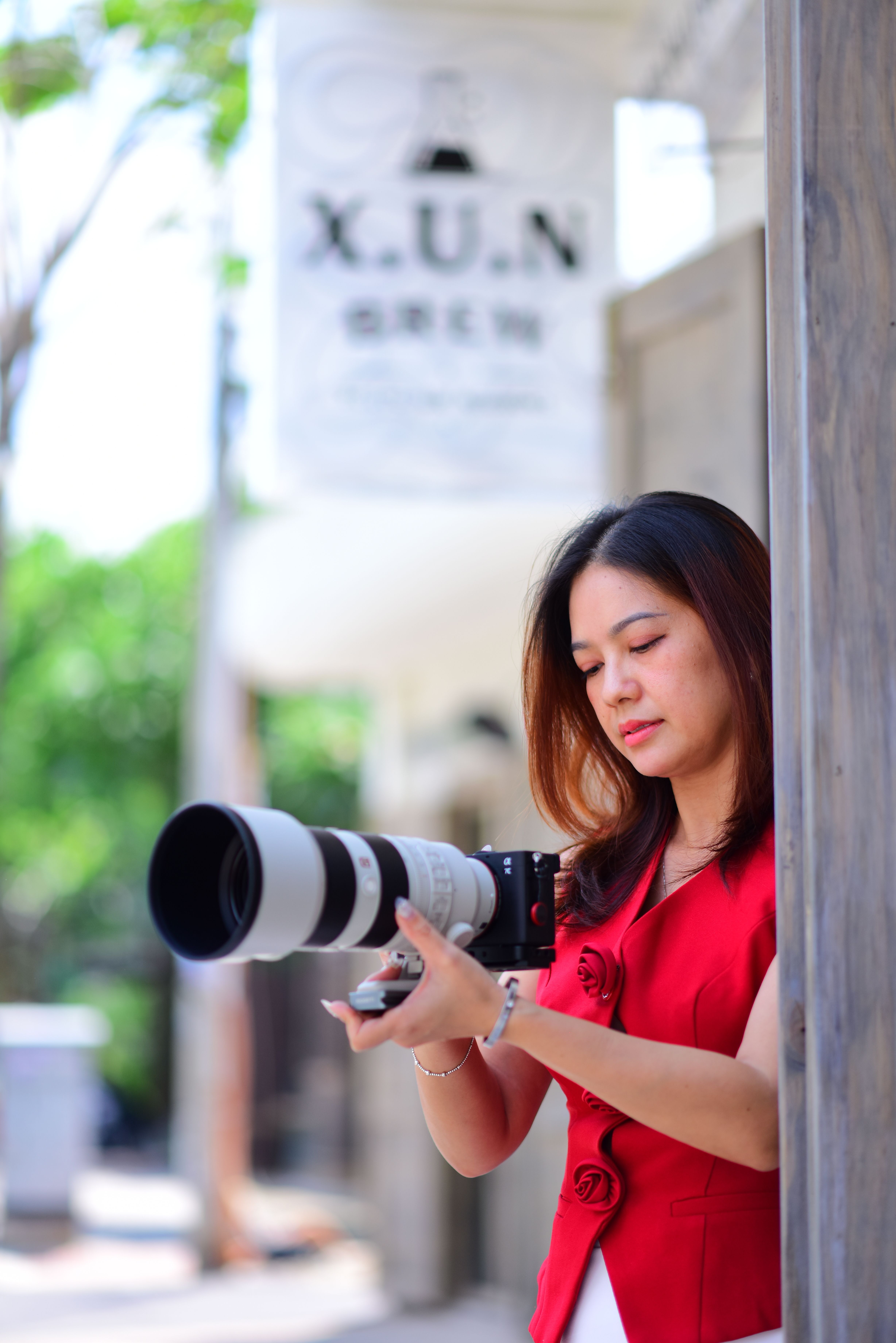 Portrait of a female photographer using a DSLR outdoors, capturing a vibrant scene.