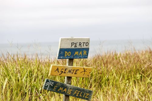 Free Vibrant beach sign in Guaratuba, Paraná, Brazil, near the ocean with a grassy background. Stock Photo