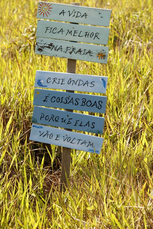 Free Colorful wooden sign with beach-themed quotes in lush grassy field, Guaratuba. Stock Photo