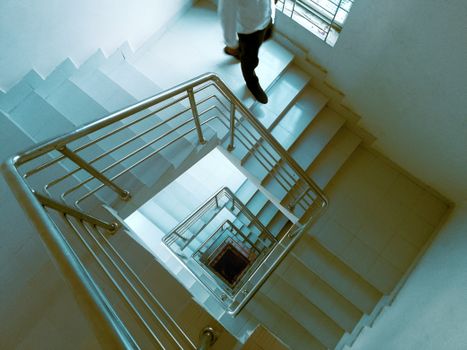 Aerial shot of a person descending a modern spiral staircase indoors.
