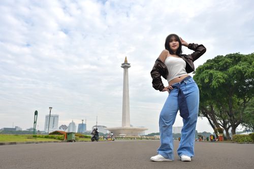Free Young woman posing confidently in front of Jakarta's National Monument, Monas. Stock Photo