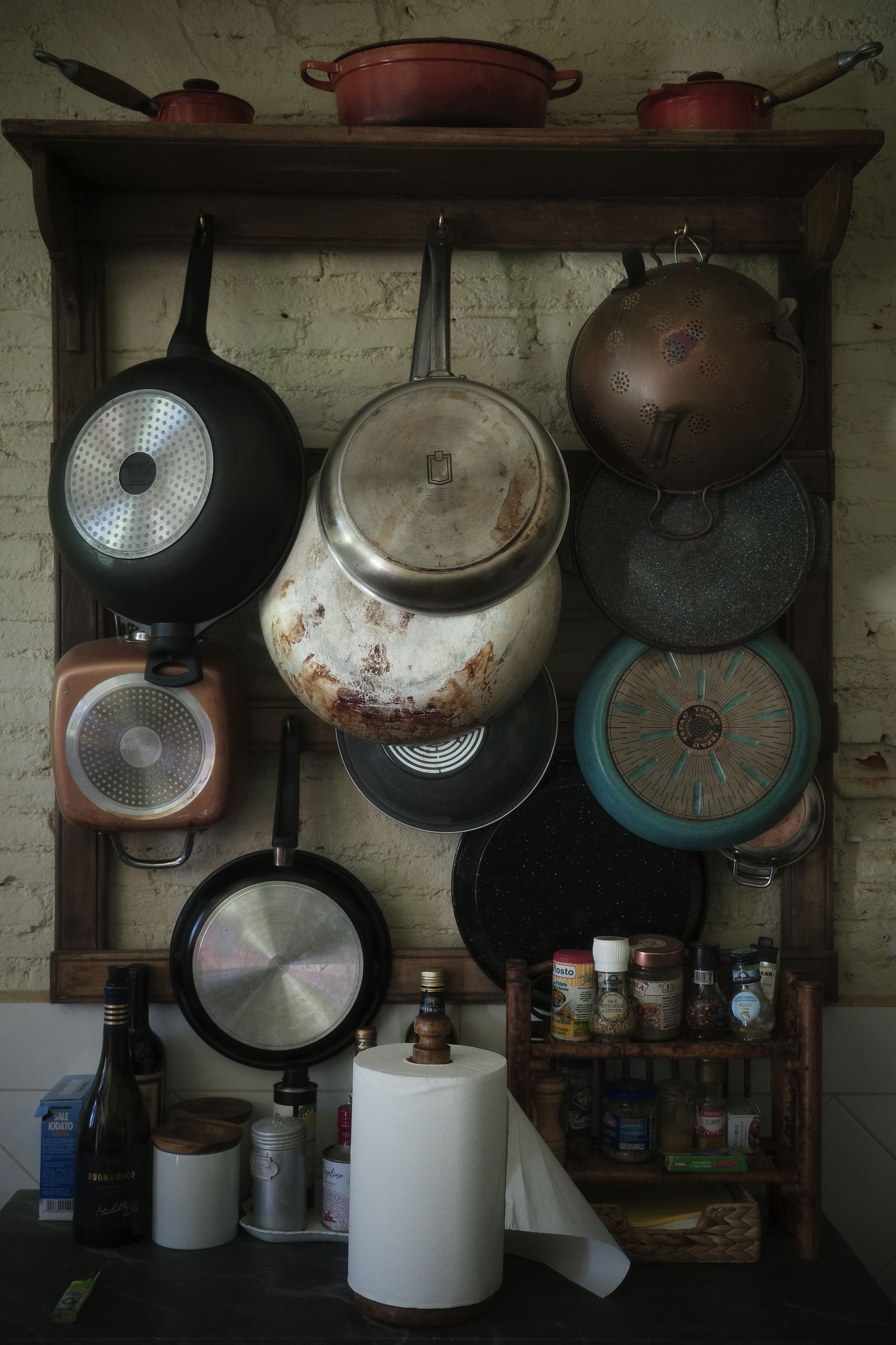 Cozy kitchen corner with a variety of hanging pans and spices, exuding rustic charm.