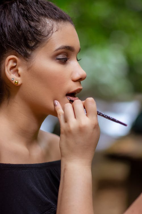 Woman Applying Lipstick on Lips of Woman in Black Top