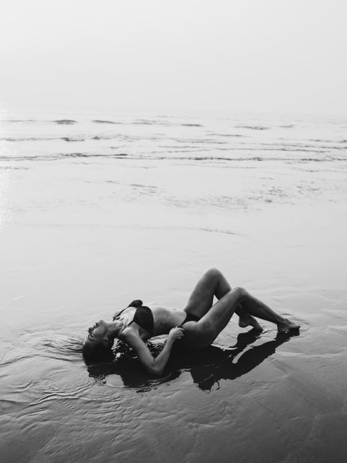 Free Woman lying on a calm beach in a bikini, embracing serenity and relaxation. Stock Photo