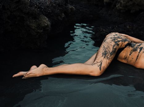 Mud-covered legs gracefully resting in calm, reflective water amidst rocky surroundings.