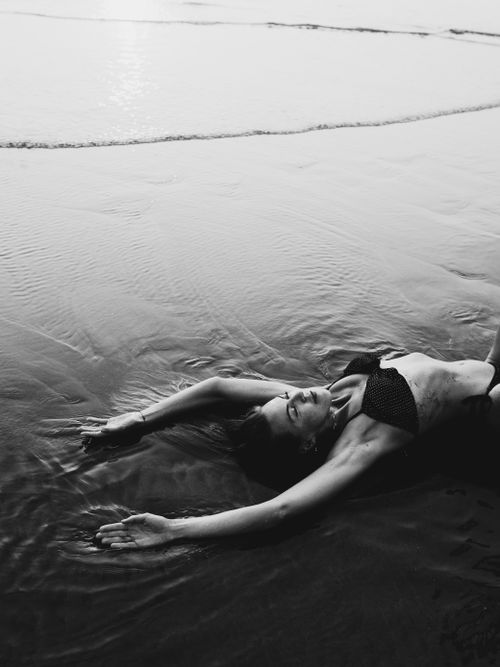 Free Woman in bikini laying on the beach at twilight, serene and calm. Stock Photo