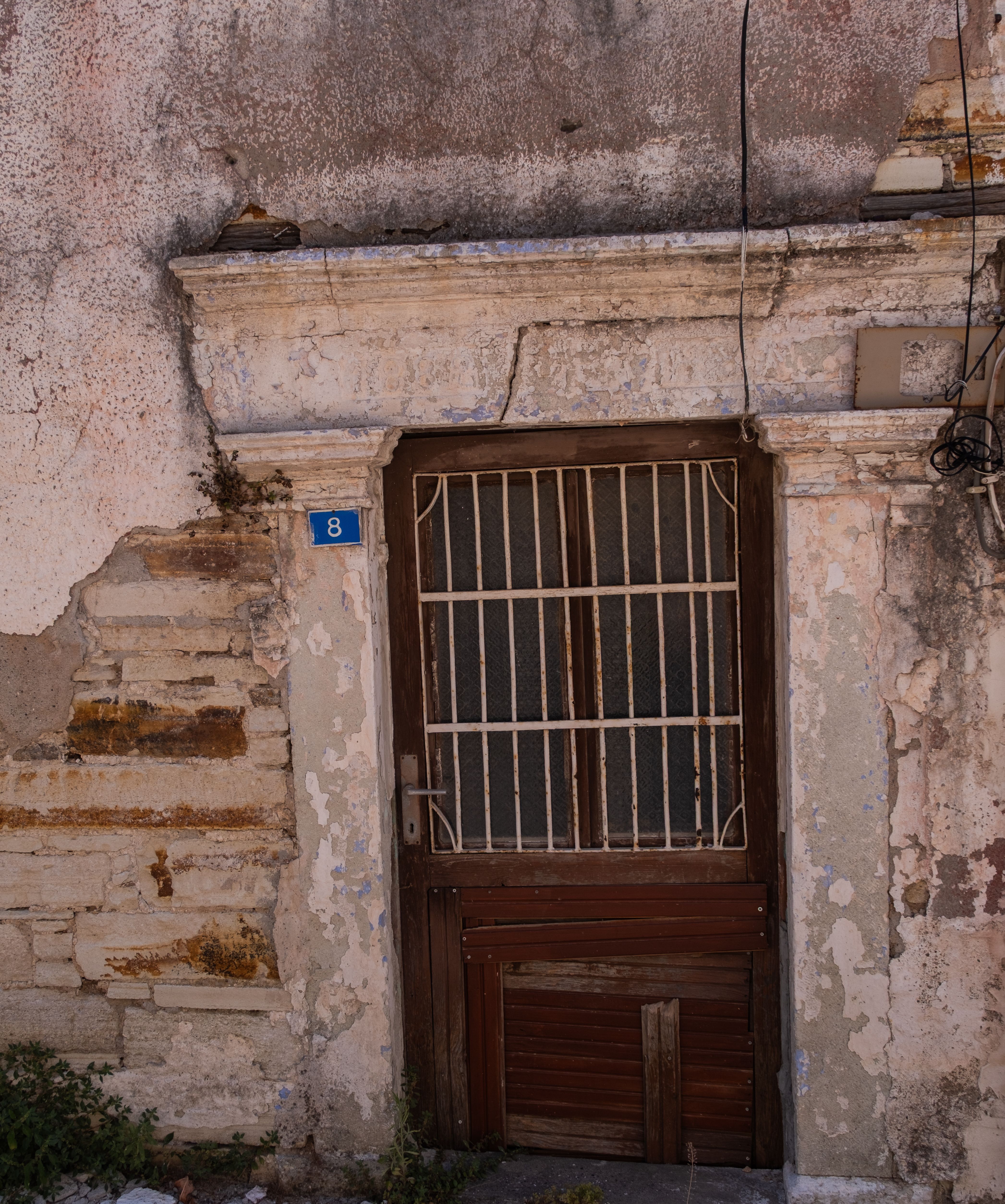 Vintage wooden door on a rustic stone wall at house number 8 in Foça, İzmir, Türkiye.
