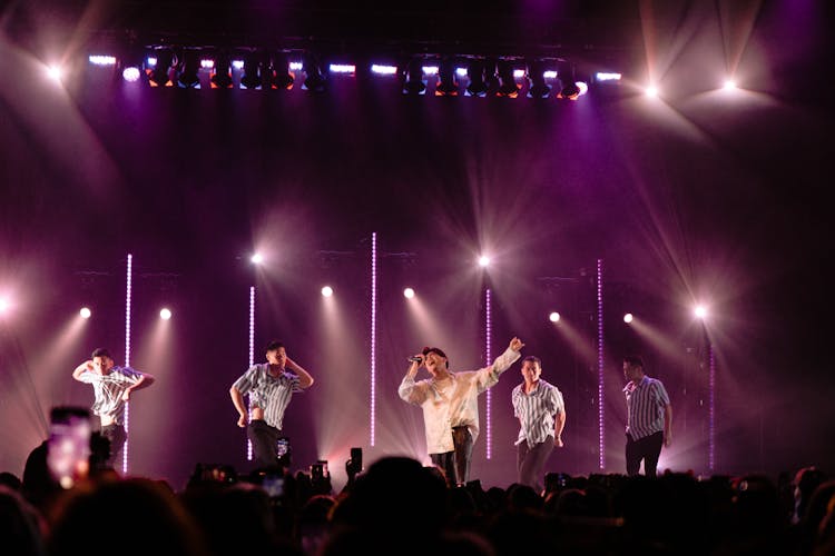 Photo Of Man Singing On Stage With Backup Dancers