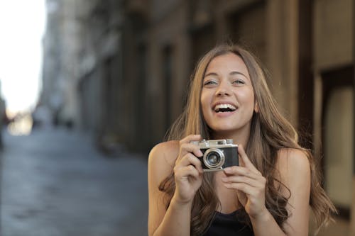 Woman in Black Tank Top Holding Silver Camera