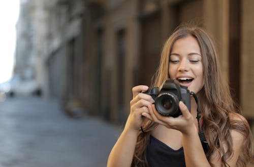 Woman in Black Tank Top Holding Black Dslr Camera