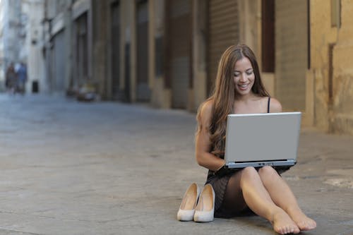 Woman Sitting on Floor While Using Laptop