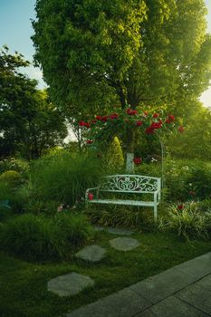 Serene garden setting with ornate white bench and lush greenery.