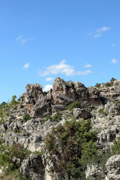 Free A scenic view of rocky formations against a bright blue sky with scattered clouds. Stock Photo