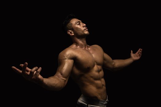 Muscular male model posing confidently in a dramatic lighting environment, showcasing fitness and strength.