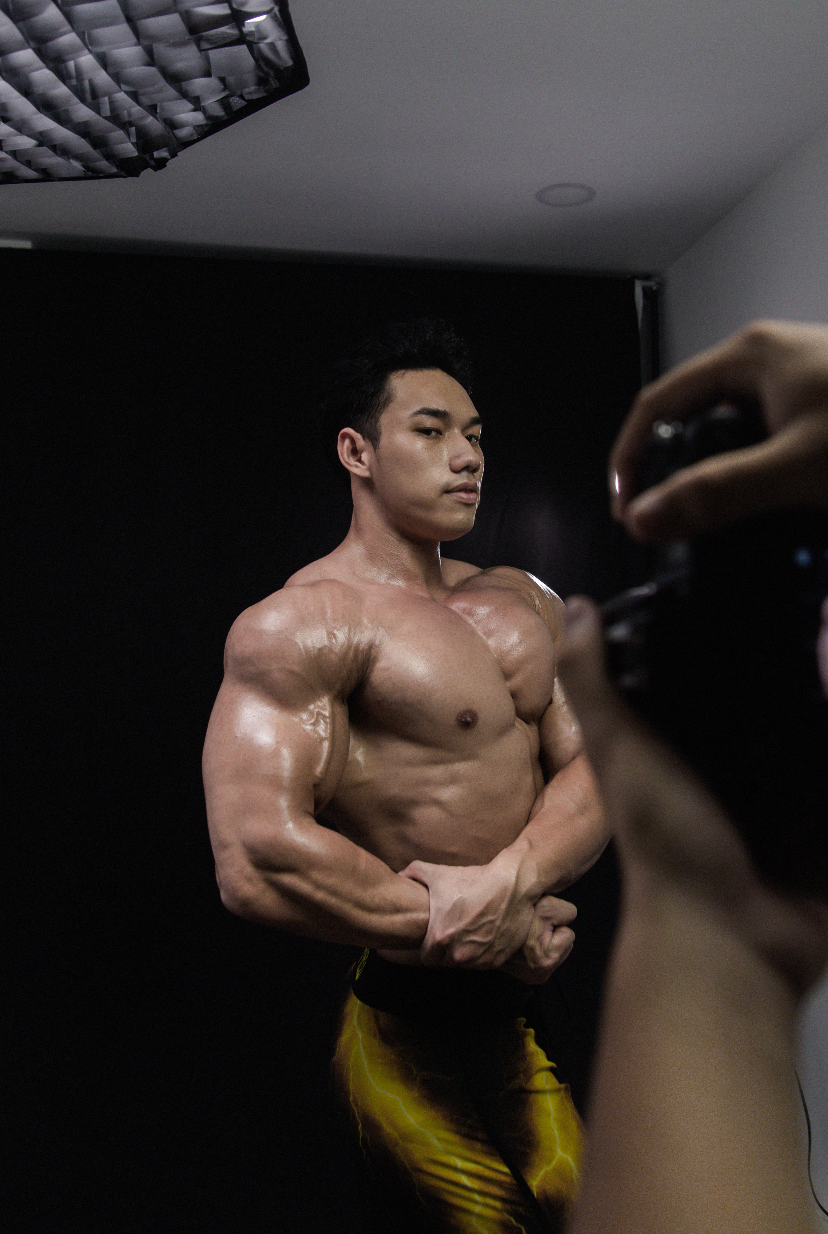 Muscular man posing in a photography studio showcasing bodybuilding physique.