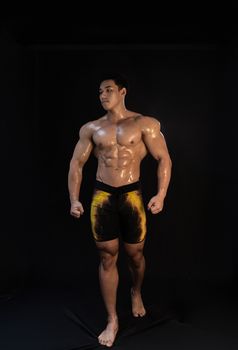 Strong bodybuilder showcasing defined muscles standing confidently in a studio.