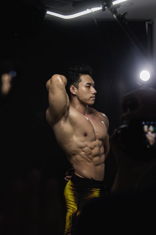 Free Athletic male model posing under studio lighting showcasing muscular physique and confidence. Stock Photo