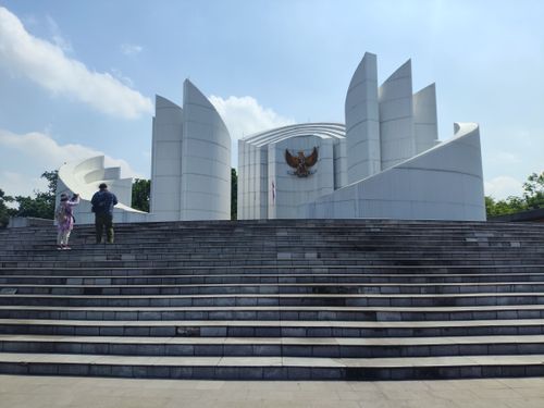 Free Tourists explore a striking modern architectural landmark in Jawa Barat, Indonesia under a clear blue sky. Stock Photo