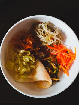 Top view of a vibrant Korean bibimbap dish with assorted vegetables in a white bowl.
