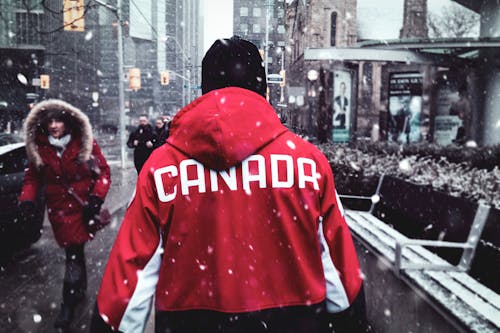 Man in Red Hoodie Walking on Sidewalk