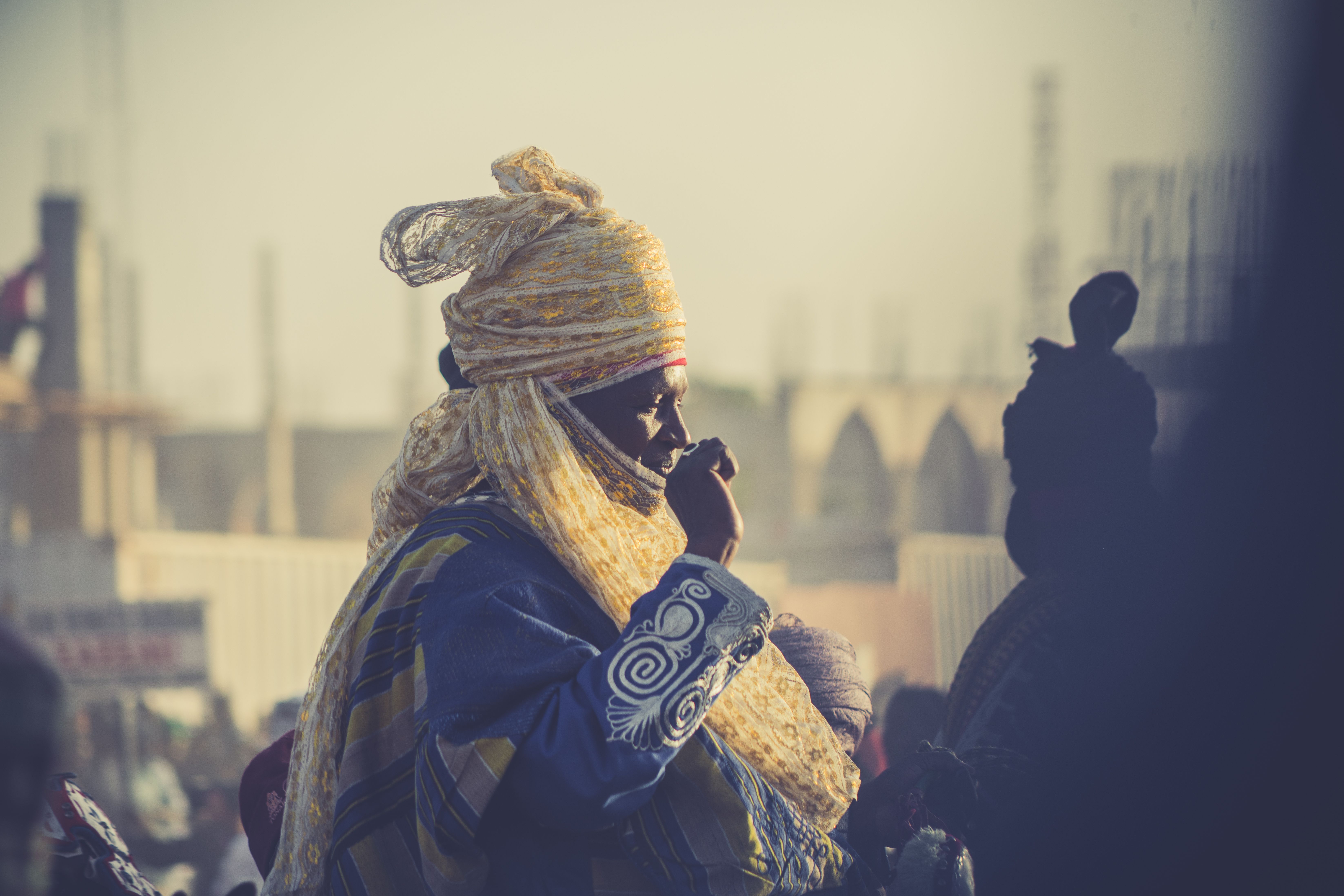 A person in traditional African clothing captured in a bustling street, showcasing cultural attire.