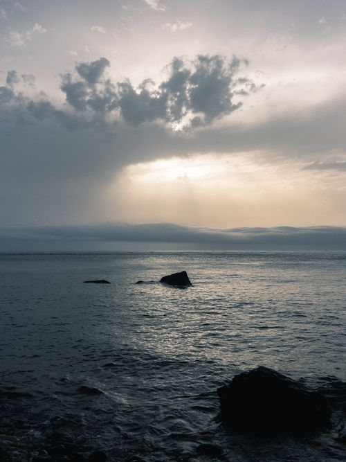 Free Experience the serene beauty of a tranquil ocean at sunset, with dramatic clouds overhead. Stock Photo
