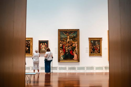 Free Visitors explore fine art paintings in a València gallery, capturing cultural appreciation. Stock Photo