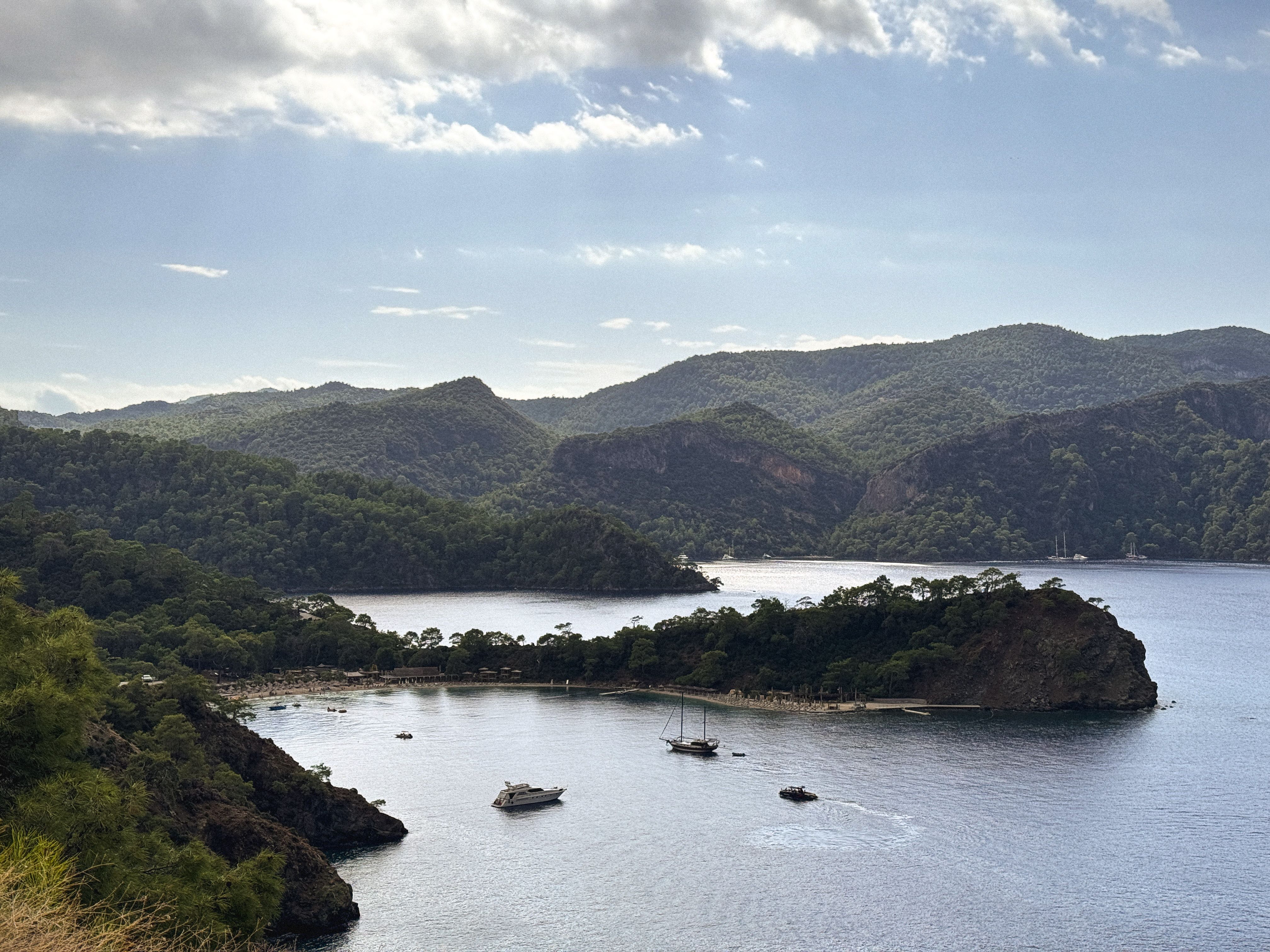 A tranquil view of a bay with sailboats surrounded by lush hills in Fethiye, Turkey.