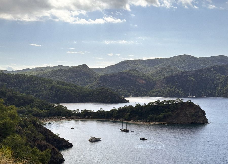 A tranquil view of a bay with sailboats surrounded by lush hills in Fethiye, Turkey.