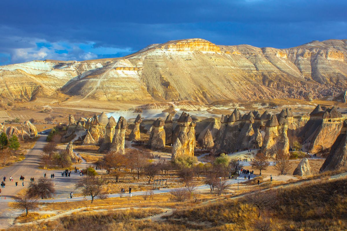 Beautiful landscape of Cappadocia's iconic rock formations with tourists exploring.