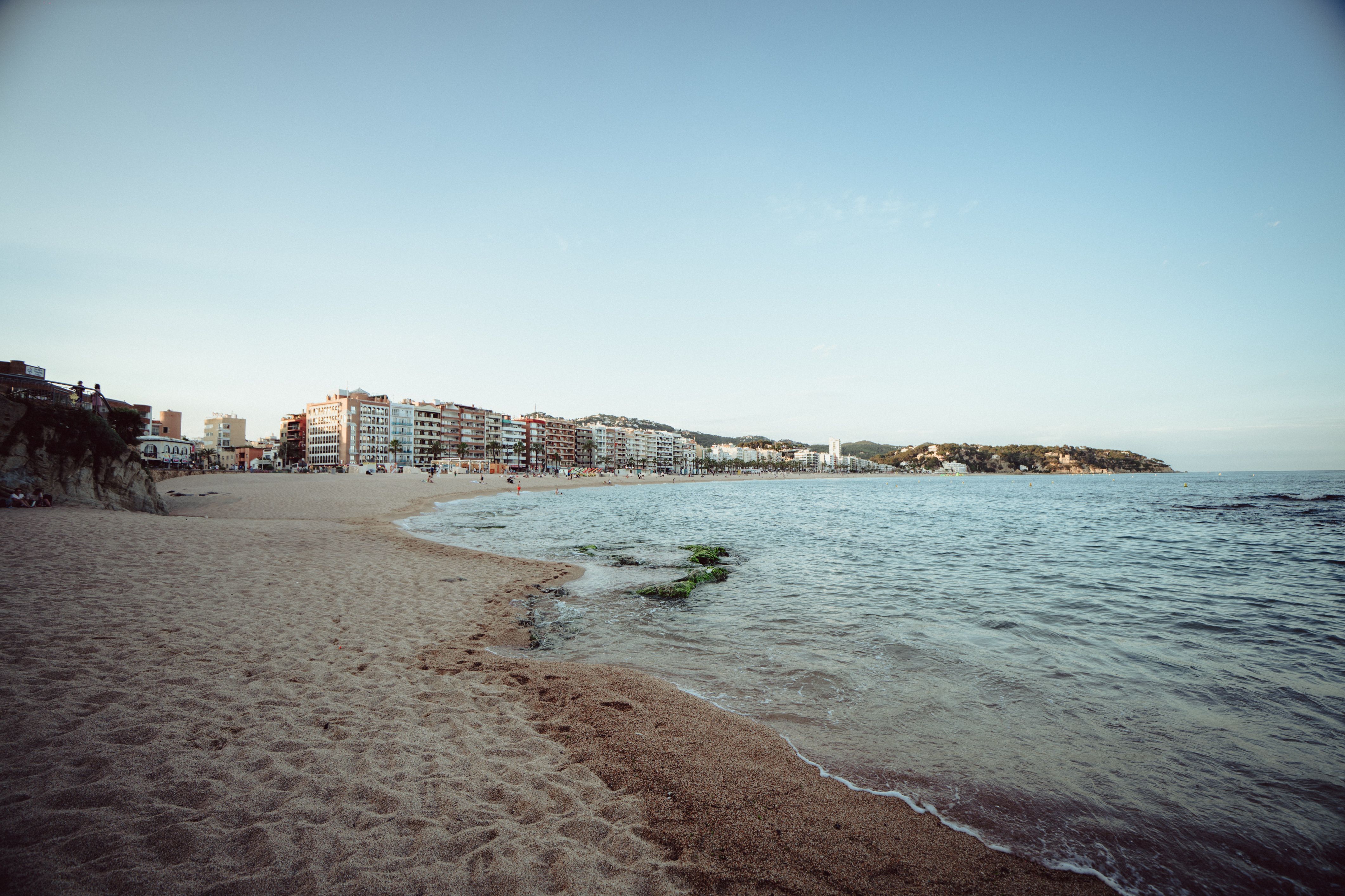 Peaceful beach view in Lloret de Mar, Spain at twilight with calm waters and coastal buildings.