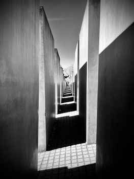 Dramatic black-and-white perspective of Berlin's Holocaust Memorial with strong shadows.