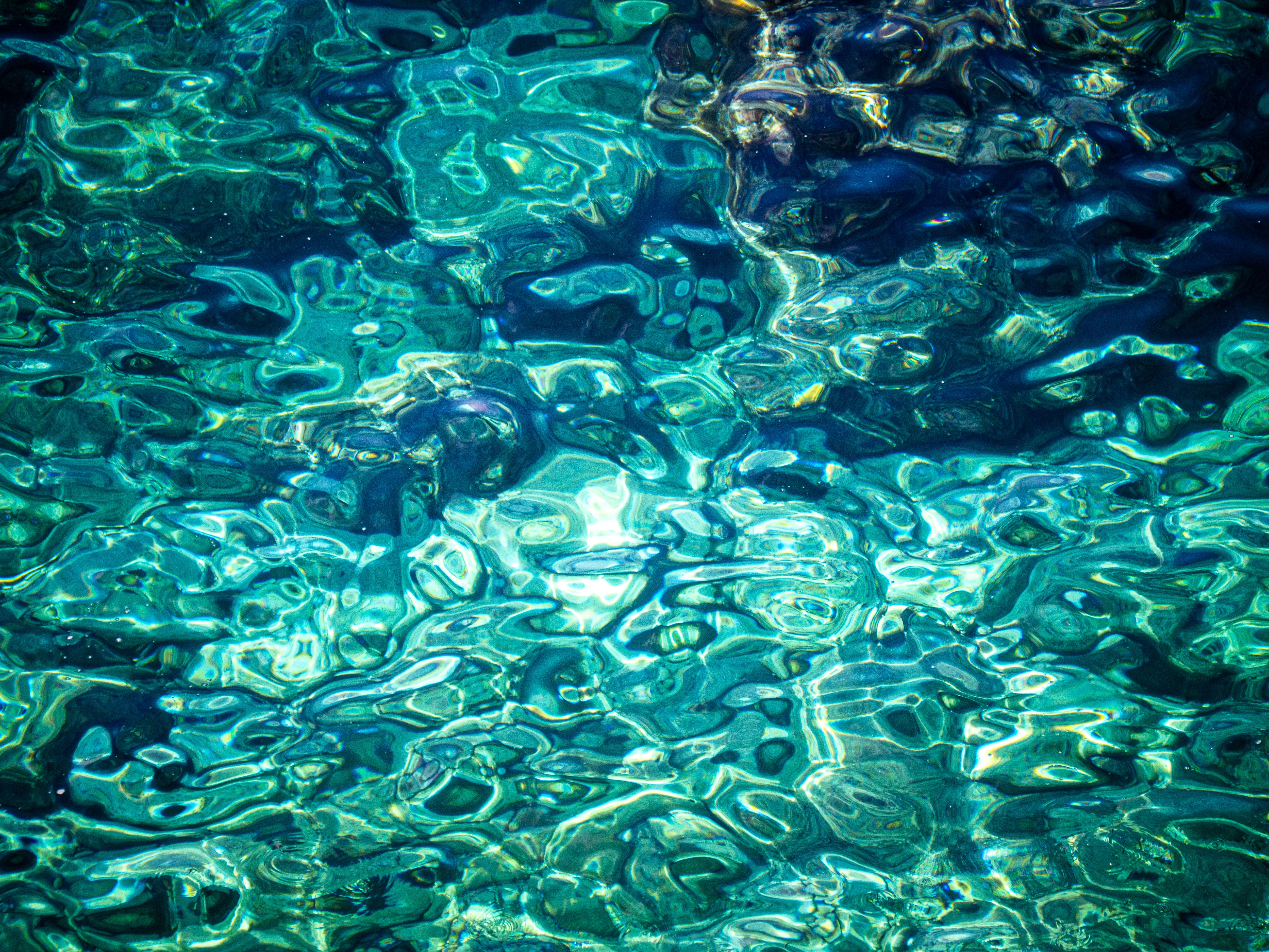 Vibrant rippling turquoise water with stunning sunlit patterns creating an abstract natural artwork.