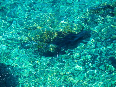 Vibrant turquoise water with sunlight creating abstract patterns on the surface.